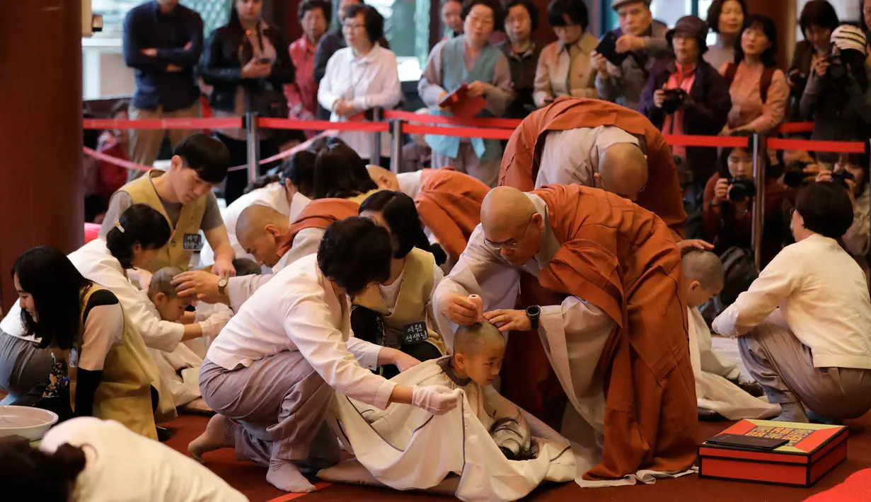 Seorang biksu mencukur rambut bocah laki-laki dalam seremonial ulang tahun Buddha di kuil Jogye, Seoul, Rabu (2/5). Sepuluh anak terpilih mendapatkan pengalaman menjadi biksu dalam rangkaian acara peringatan hari lahir Buddha (AP/Lee Jin-man)