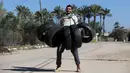 Aksi Mohamed Barka, pria yang dijuluki "Super Hero" asal Palestina saat mengangkat sejumlah ban menggunakan giginya di Deir Al-Balah, Gaza Tengah, Kamis (4/2). (MOHAMMED ABED/AFP)