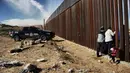 Sebuah keluarga saling melepas rindu melalui dinding perbatasan antara Meksiko dan Amerika Serikat di Ciudad Juarez, 10 Desember 2017. Suasana di gerbang perbatasan jadi mengharukan ketika mereka mulai menangis bahagia. (Herika MARTINEZ/AFP)
