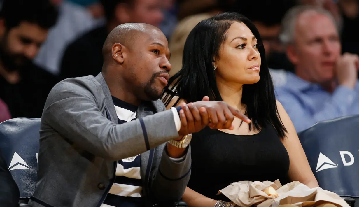 Petinju Floyd Mayweather Jr dan Jamie Lynn duduk di tepi lapangan saat menonton pertandingan NBA antara Los Angeles Lakers melawan Washington Wizards di Los Angeles (28/3). (AP Photo/Danny Moloshok)