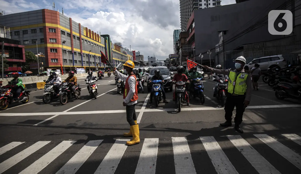 Petugas mengatur lalu lintas untuk warga menyeberang jalan menggunakan pelican crossing di kawasan Glodok, Jakarta, Sabtu (22/1/2022). Halte Glodok baru merupakan halte lama yang terdampak proyek pembangunan MRT Fase II. (Liputan6.com/Johan Tallo)
