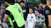 Pemain depan Inter Miami asal Argentina, Lionel Messi (tengah-kiri), dan putranya, pemain U-12 Inter Miami, Thiago Messi (tengah-kanan), tiba di lapangan untuk pertandingan perdana Inter Miami CF Youth International Cup antara Inter Miami U-12 dan Orlando SC U-12 di Chase Stadium di Fort Lauderdale, Florida, pada tanggal 24 Mei 2024. (Chris ARJOON/AFP)