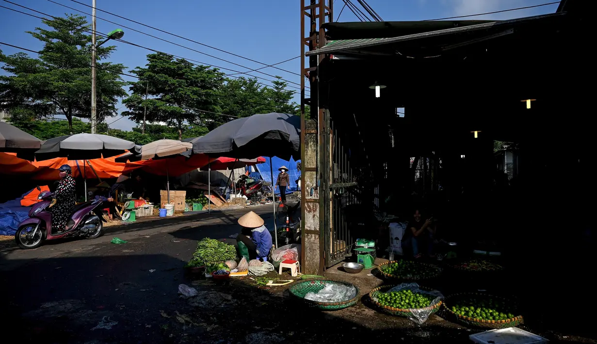 Seorang penjual sayuran menunggu pelanggan di pasar grosir di Hanoi (26/8/2020). (AFP Photo/Manan Vatsyayana)