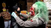 Polisi mengenakan topeng menyeramkan yang disebut "Leak" saat sosialisasi encegahan COVID-19 di pasar tradisional di Kerobokan, Denpasar, Kamis (14/5/2020). Kegiatan itu mengimbau masyarakat agar selalu mengenakan masker, rutin mencuci tangan, menjaga jarak, serta tidak mudik. (SONNY TUMBELAKA/AFP)