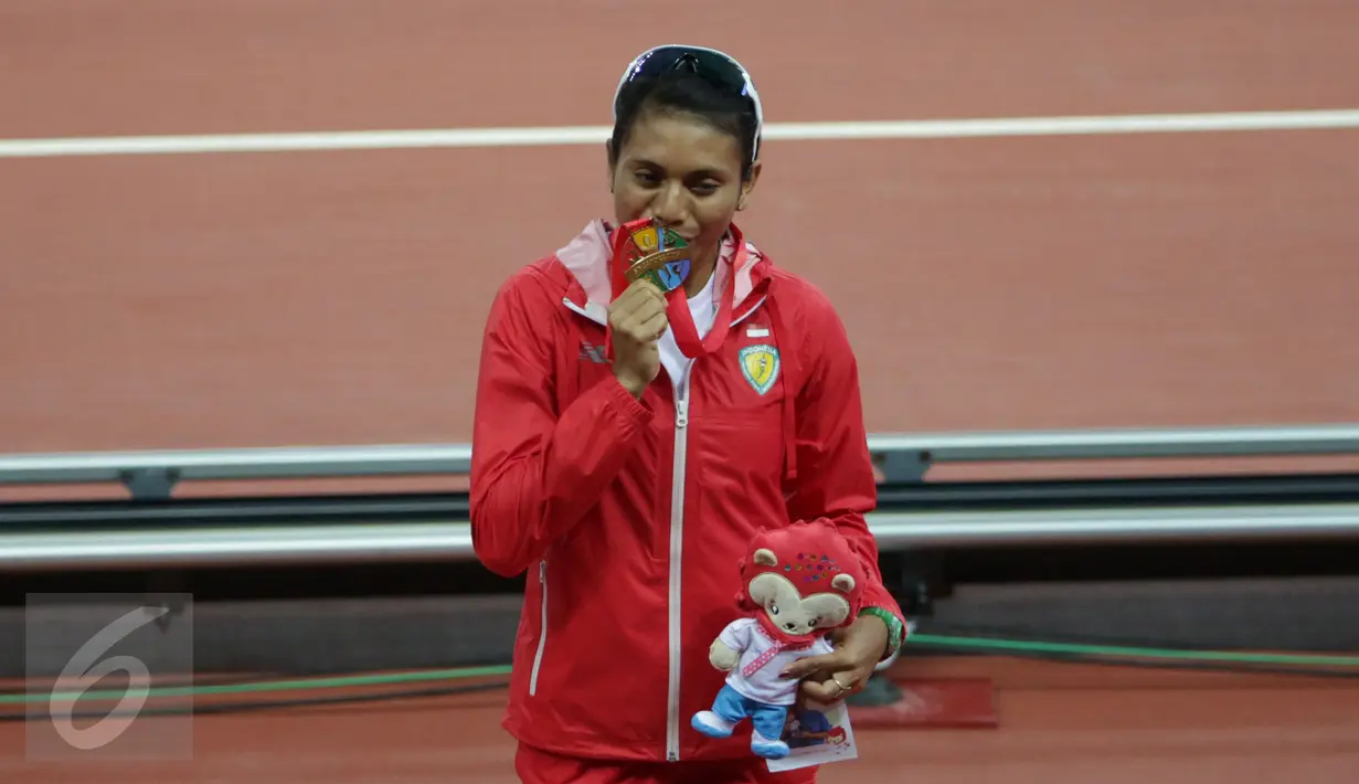 Atlet lompat jauh Indonesia, Maria Londa berhasil meraih emas di nomor lompat jauh putri SEA Games 2015 di National Stadium, Singapura, Rabu (10/6/2015). Maria mencium medali usai pengalungan. (Liputan6.com/Helmi Fithriansyah)