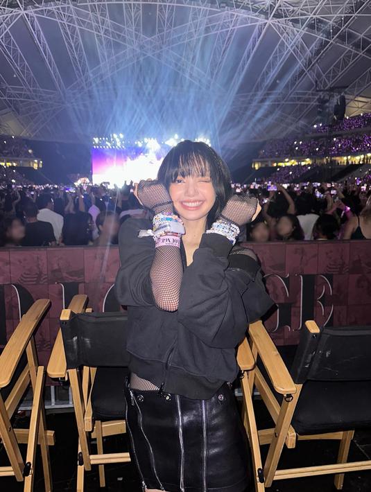 Lisa Blackpink tersenyum sambil memamerkan gelang persahabatan dengan background panggung Eras Tour. (Foto: Instagram/ lalalalisa_m)