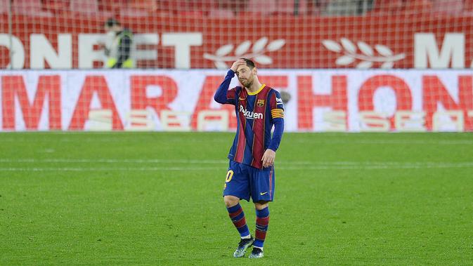 Striker Barcelona, Lionel Messi, memegang kepalanya usai ditaklukkan Sevilla pada laga leg pertama semifinal Copa del Rey di Estadio Ramon Sanchez Pizjuan, Kamis (11/2/2021). Barcelona tumbang dengan skor 2-0. (AFP/Cristina Quicler)