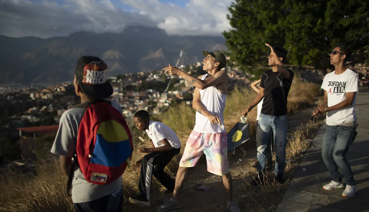 Para pemuda menerbangkan layang-layang dalam acara peringatan 400 tahun permukiman kumuh Petare di Caracas, Venezuela (17/2/2021). Kemiskinan tetap menjadi kendala utama perkembangan kota ini. (AP Photo/Ariana Cubillos)