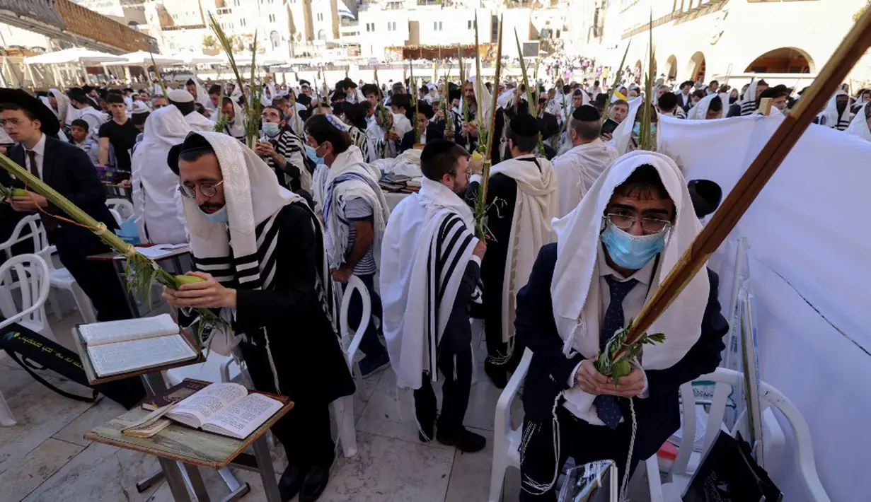 Umat Yahudi memanjatkan doa saat memperingati Hari Raya Sukkot di Tembok Barat, Kota Tua Yerusalem, 22 September 2021. Sukkot adalah hari raya untuk memperingati eksodus bangsa Israel dari Mesir sekitar 3200 tahun yang lalu. (Emmanuel DUNAND/AFP)