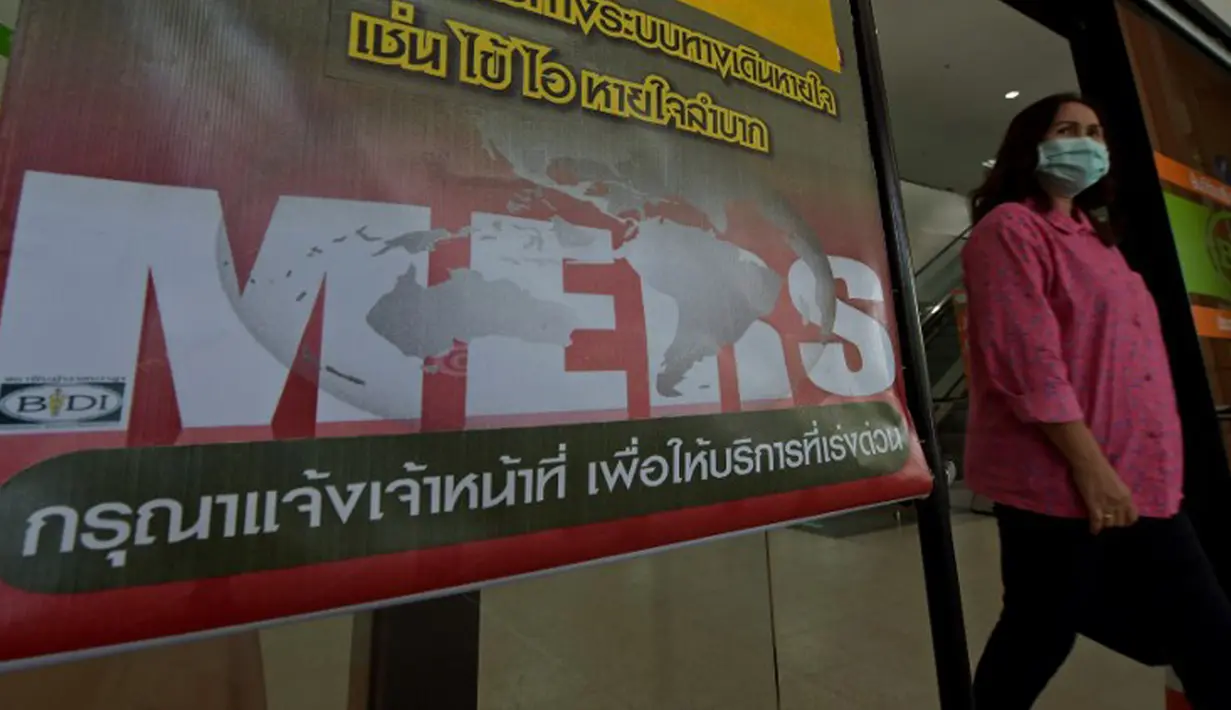 Seorang wanita Thailand berjalan memakai masker melewati pengumuman wabah MERS di Nonthaburi, Thailand, (19/6/2015). Pemerintah Thailand mengumumkan bahwa seorang pria 75 tahun asal Oman positif terjangkit virus MERS. (AFP PHOTO/Pornchai KITTIWONGSAKUL)