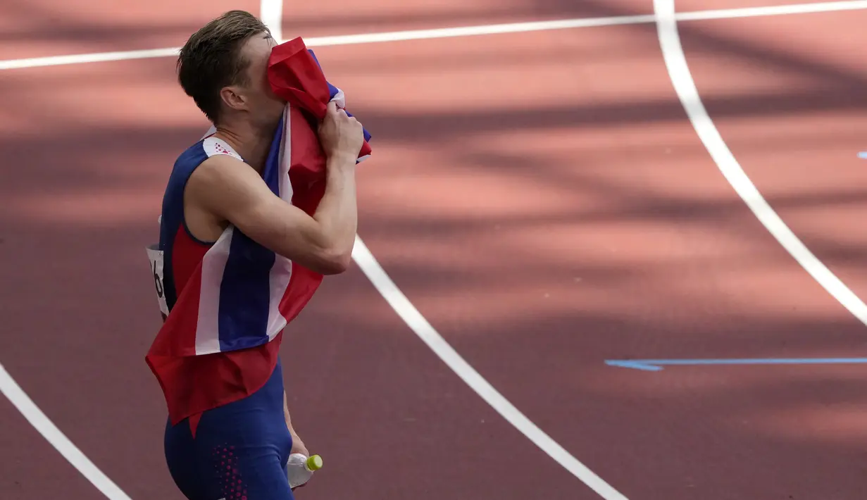 Atlet Norwegia Karsten Warholm mencium saat bendera merayakan kemenangannya pada final lari gawang 400m putra Olimpiade Tokyo 2020 di Olympic Stadium, Selasa (3/8/2021). Warholm sukses memecahkan rekor dunia lari gawang 400 meter putra dengan catatan waktu 45,95 detik. (AP Photo/Charlie Riedel)