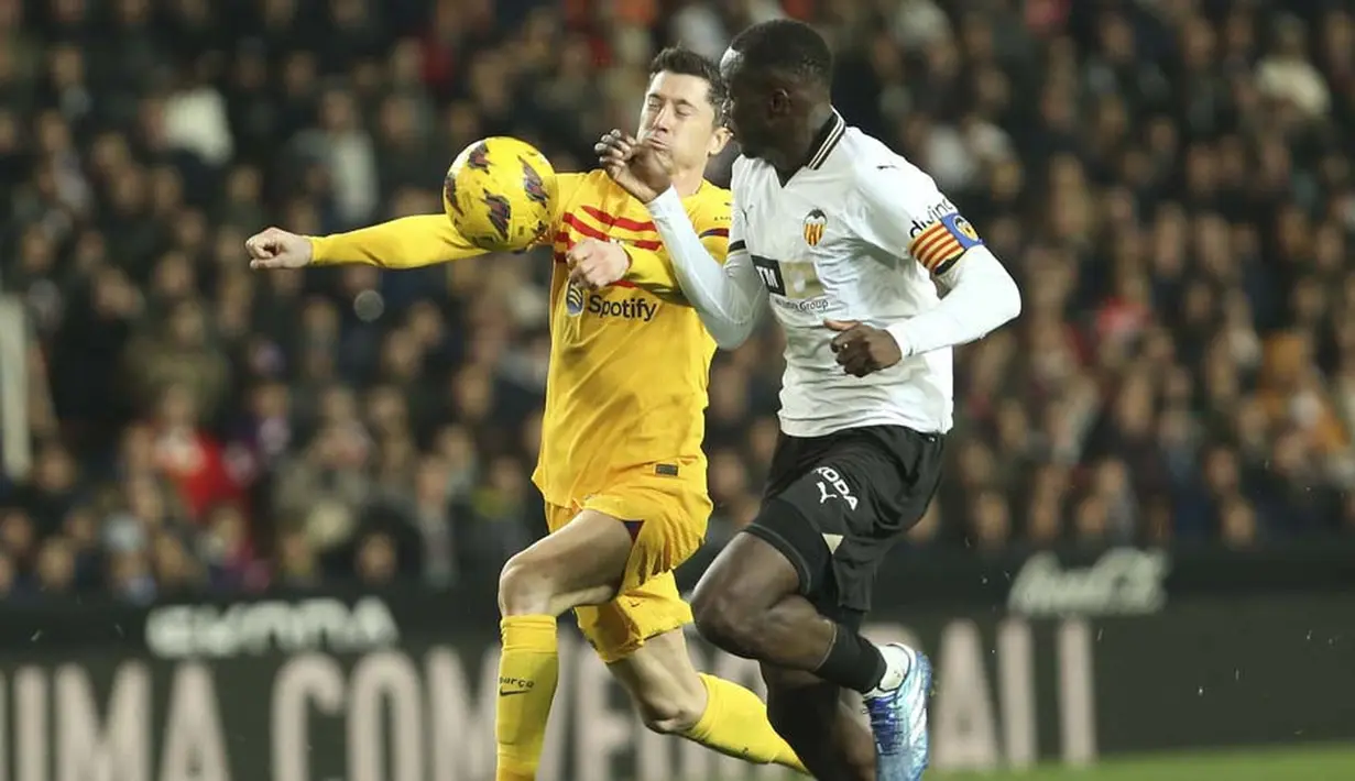 Pemain Barcelona, Robert Lewandowski, berusaha melewatkan pemain Valencia, Mouctar Diakhaby, pada laga pekan ke-17 La Liga 2023/2024 di Stadion Mestalla, Minggu (17/12/2023). (AP Photo/Alberto Saiz)
