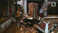 Warga membersihkan sisa lumpur yang tertinggal di permukiman mereka yang ada di sekitar jalan layang Kalibata-Cililitan, Jakarta, Rabu (5/3/2025). (Liputan6.com/Angga Yuniar)