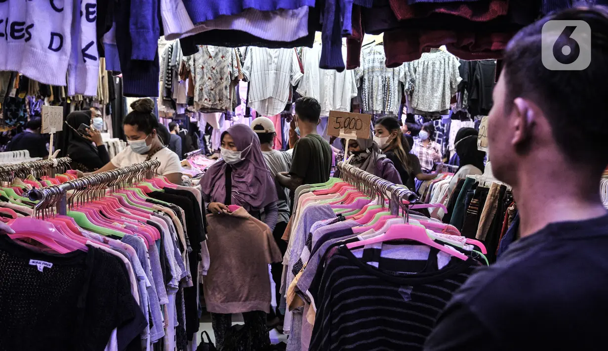 Pedagang mengamati pengunjung memilih pakaian bekas impor di Pasar Senen, Jakarta, Kamis (4/3/2021). Rudi (34) salah satu pedagang mengungkapkan penjualan pakaian bekas impor di Pasar Senen merosot hingga 50 persen sejak awal pandemi COVID-19 melanda Ibu Kota. (merdeka.com/Iqbal S. Nugroho)