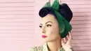 Masih dengan tampilan vintagenya. Kali ini Claudia menghias rambutnya yang dibuat sasak tinggi itu dengan kain hijau yang dibuat seperti pita. Ia pun mengenakan kemeja bermotif floral yang dipadukan rok berempelnya. (Instagram/miss_adinda_mae)