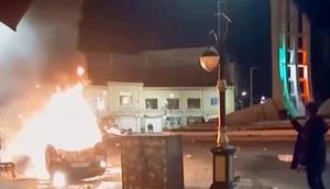 Cuplikan gambar dari video yang dirilis pada Jumat (9/1/2026) oleh televisi pemerintah Iran memperlihatkan seorang pria memegang sebuah perangkat untuk mendokumentasikan kendaraan yang terbakar selama aksi protes massal pada malam hari di Zanjan, Iran. (Dok. Televisi pemerintah Iran melalui AP)