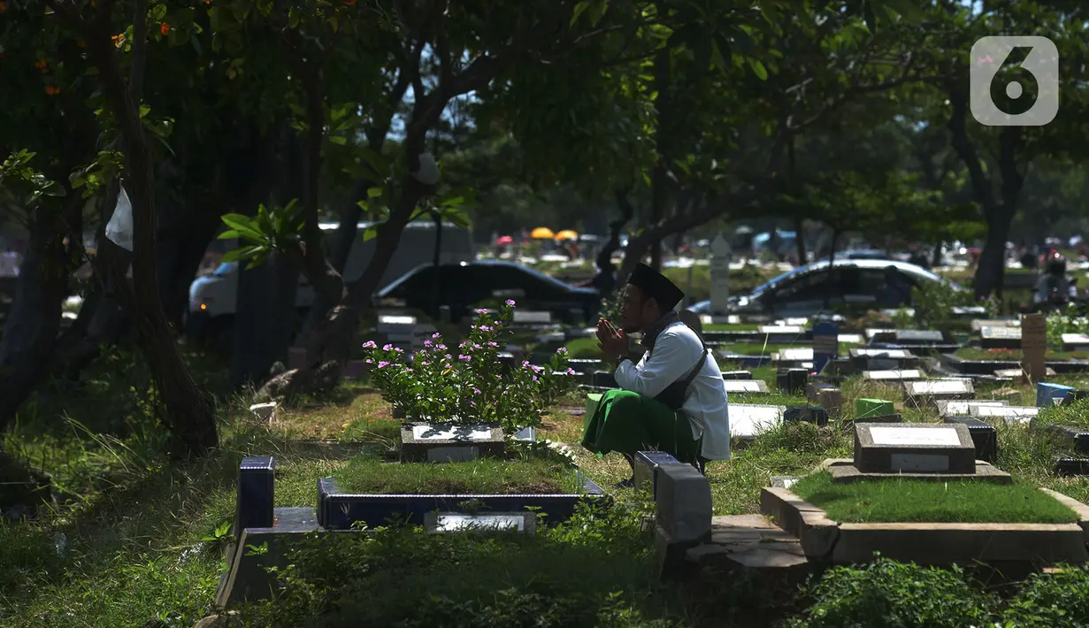 Warga berdoa saat ziarah kubur pada hari kedua Idul Fitri 1441 Hijriah di Tempat Pemakaman Umum (TPU) Semper, Jakarta, Senin (25/5/2020). Di tengah pandemi Covid-19,  peziarah kubur di TPU Semper berkurang. (merdeka.com/Imam Buhori)