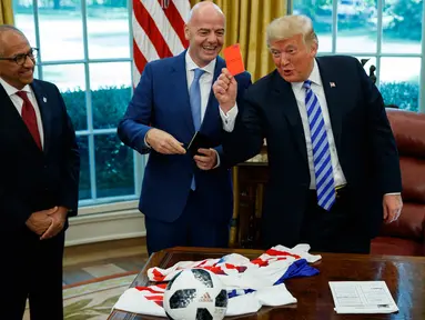Presiden AS, Donald Trump memegang kartu merah yang diberikan presiden FIFA, Gianni Infantino (tengah) selama pertemuan di Oval Office Gedung Putih, Selasa (28/8). Presiden FIFA bertemu Trump untuk membahas kesiapan Piala Dunia 2026. (AP/Evan Vucci)