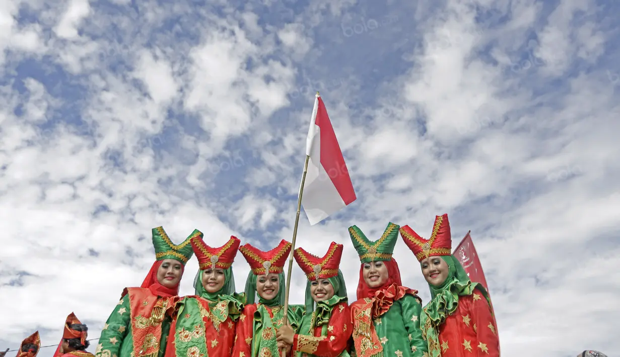 Penari dengan pakaian tradisional mengibarkan bendera Merah-Putih usai beraksi pada penutupan Tour de Singkarak 2016 di Kota Padang, Sumatera Barat, (14/8/2016). (Bola.com/Nicklas Hanoatubun)