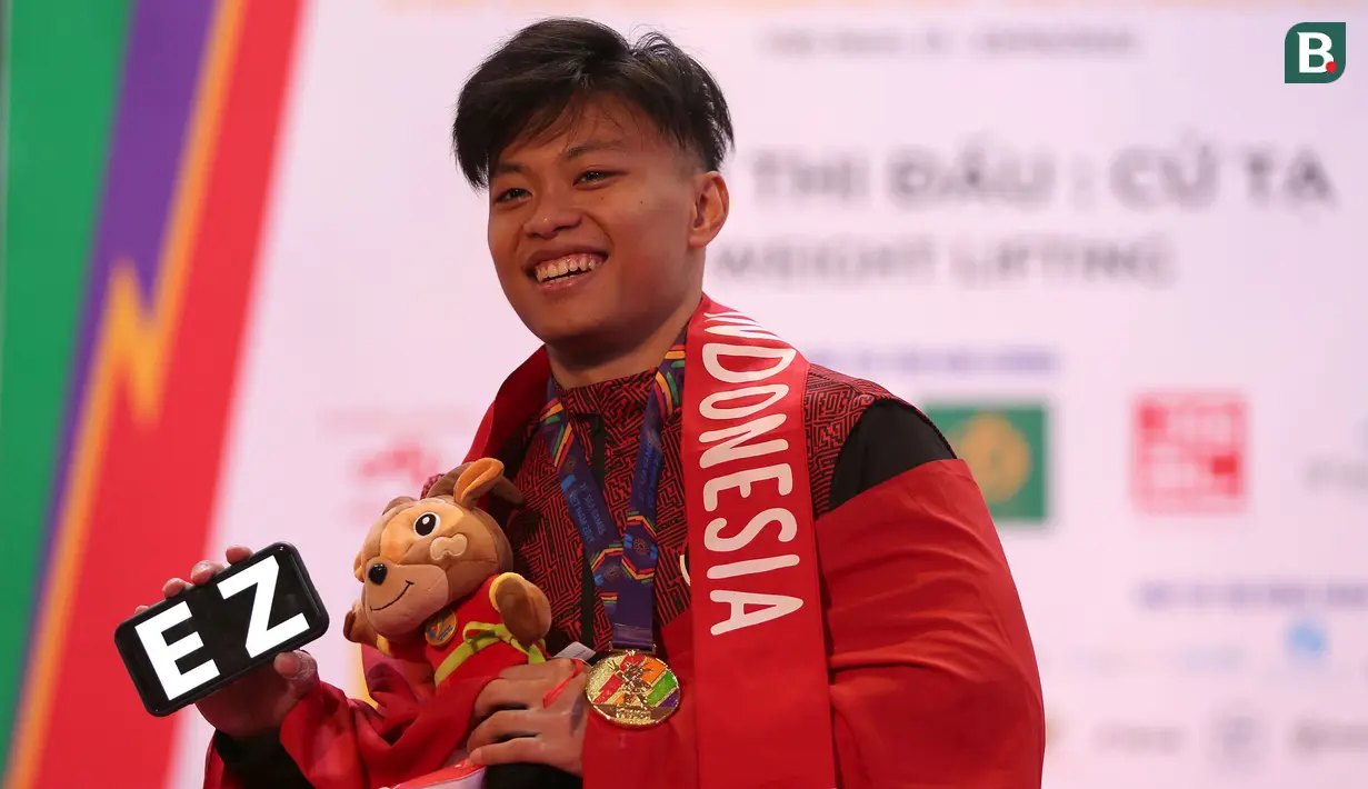 Medali emas Rahmat Erwin Abdullah di SEA Games 2021 ini sekaligus mempertahankan medali emas yang diraihnya pada SEA Games 2019 Filipina. Dengan angkatan total 345 kg, ia berhasil memecahkan rekornya sendiri yang dibuat di SEA Games 2019 Filipina dengan total angkatan 322 kg. (Bola.com/Ikhwan Yanuar)