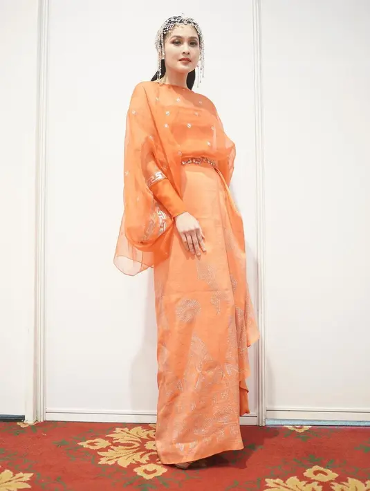 Sandra Dewi tak kalah anggun dengan dress terusan oranye bermotif. Belt emas dan headpiece bikin Sandra Dewi terlihat makin anggun [@sandradewi88]