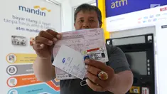 Warga menunjukkan bukti pembayaran tilang online melalui atm Bank Mandiri di Jakarta, Kamis (3/1). Bank Mandiri berkerjasama dengan Kejari Jakpus dalam penerimaan pembayaran tilang non tunai atau secara online. (Liputan6.com/Angga Yuniar)