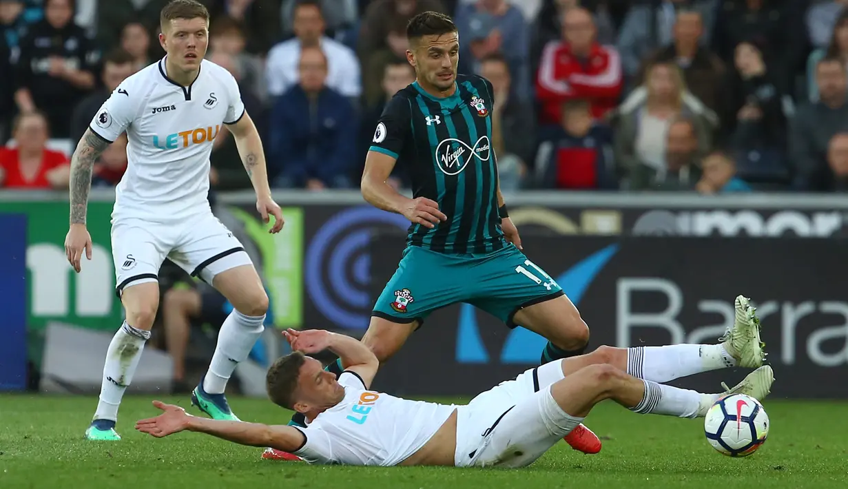 Pemain Swansea City, Andy King mencoba menghalau bola dari kaki pemain Southampton, Dusan Tadic pada lanjutan Premier League di Liberty Stadium, Swansea, (8/5/2018). Swasea City kalah dari Soton 0-1. (AFP/Geoff Caddick)