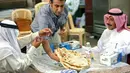Pelayan menyajikan roti Iran atau taftoon kepada pelanggan di sebuah toko di Kuwait City, Kuwait, 27 Juni 2019. Taftoon akan lebih nikmat bila disajikan saat masih panas. (YASSER AL-ZAYYAT/AFP)
