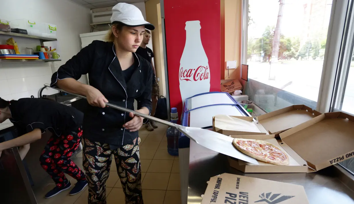 Pekerja Pizza Veterano menyiapkan pizza untuk tentara Ukraina yang bertugas di garis depan menghadapi separatis pro-Rusia di Mariupol, 19 Juli 2018. Kedai ini memperkejakan para veteran dan warga yang mengungsi akibat perang. (AFP/Aleksey FILIPPOV)