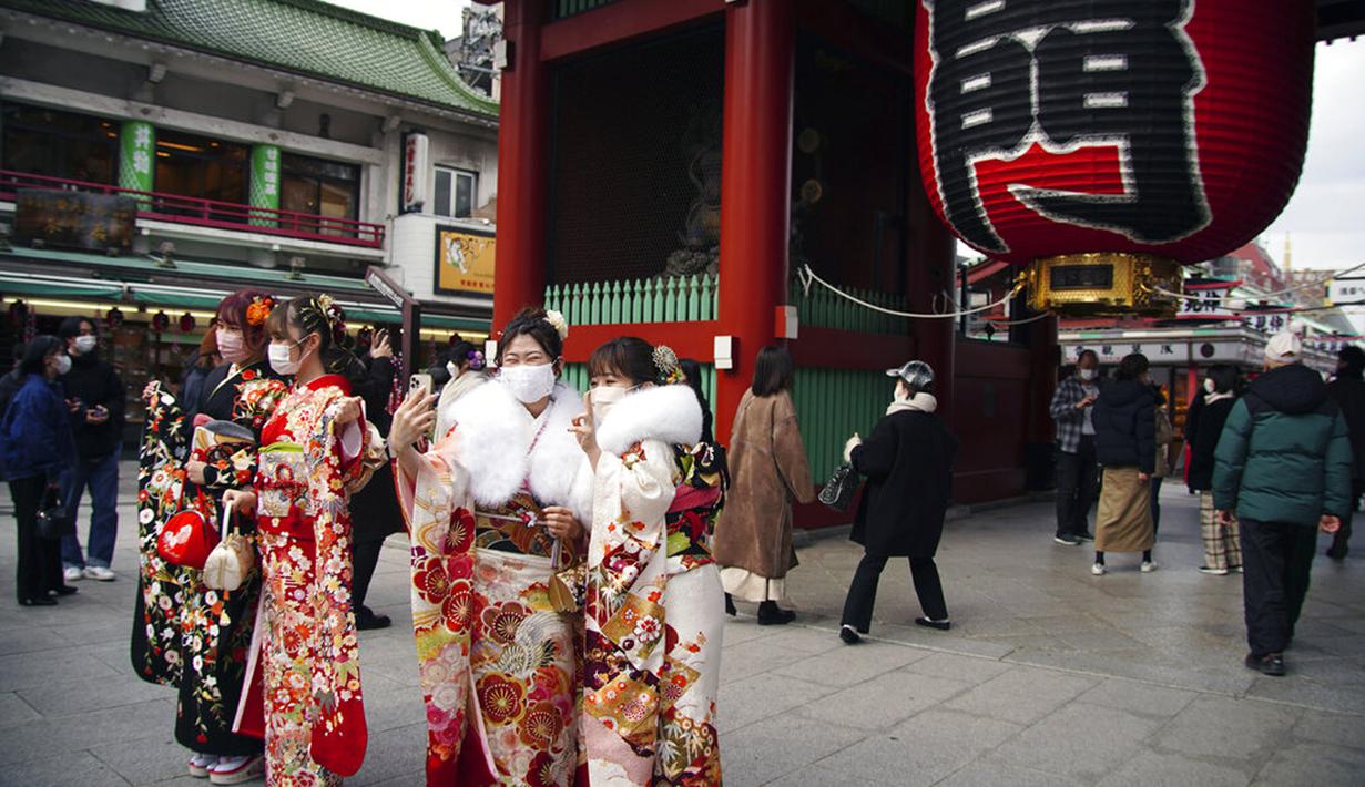 Para wanita berbaju kimono yang baru menginjak usia 20 tahun berfoto dekat Kuil Sensoji di Distrik Asakusa, Tokyo, Jepang, Senin (10/1/2022). Coming of Age Day diadakan setiap tahun pada Senin kedua bulan Januari untuk merayakan remaja Jepang menjadi dewasa. (AP Photo/Eugene Hoshiko)