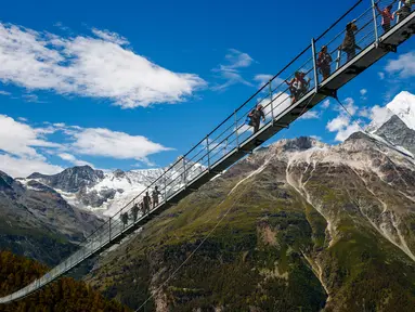 Wisatawan berjalan di atas jembatan gantung yang baru saja diresmikan di Kota Zermatt, Swiss, 29 Juli 2017. Jembatan sepanjang hampir 500 meter ini disebut-sebut sebagai jembatan gantung pejalan kaki terpanjang di dunia (Valentin Flauraud/Keystone via AP)