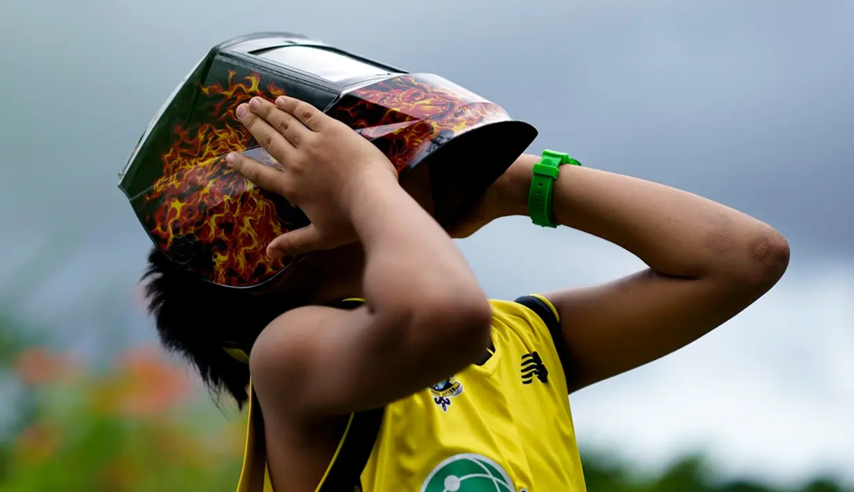 Seorang anak laki-laki memegang masker las untuk melindungi penglihatannya saat masyarakat berkumpul untuk melihat Gerhana Matahari Cincin Api di Panama City, Panama, Sabtu (14/10/2023). Awan dan hujan di Panama City membuat Gerhana Matahari Cincin Api tidak terlihat. (AP Photo/Arnulfo Franco)