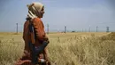 Seorang sukarelawan Pasukan Perlindungan Masyarakat Kurdi menjaga ladang gandum dari kebakaran atau penjarahan di sekitar kota Tarbesbeyeh, yang juga dikenal sebagai al-Qahtaniyah dalam bahasa Arab, di Gubernuran Hasakeh, Suriah timur laut, dekat perbatasan Turki, 30 Mei 2024. (Delil SOULEIMAN / AFP)