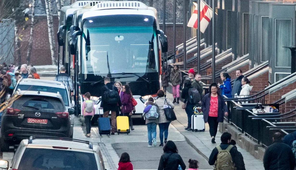 Staf diplomat yang diusir dari Rusia membawa barang mereka menuju bus yang menunggu di Kedutaan Besar AS, Moskow, Kamis (5/4). Kelompok pertama yang terdiri dari 60 diplomat bersama keluarga mereka meninggalkan kompleks Kedubes AS. (AP/Pavel Golovkin)