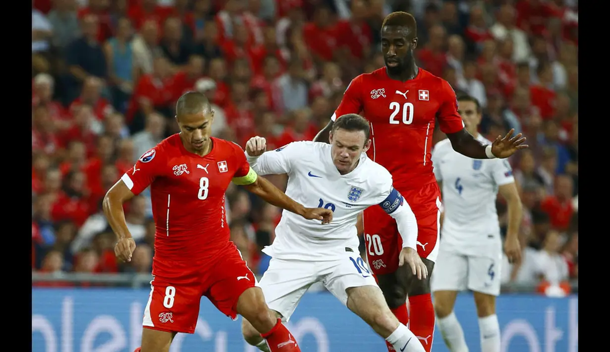 Dua pemain Timnas swiss, Johan Djourou dan Goekhan Inler (kanan), mencoba menahan pergerakan penyerang Inggris, Wayne Rooney, saat berlaga di kualifikasi Euro 2016 di Stadion St Jakob-Park, Basel , (9/9/2014). (REUTERS/Ruben Sprich)