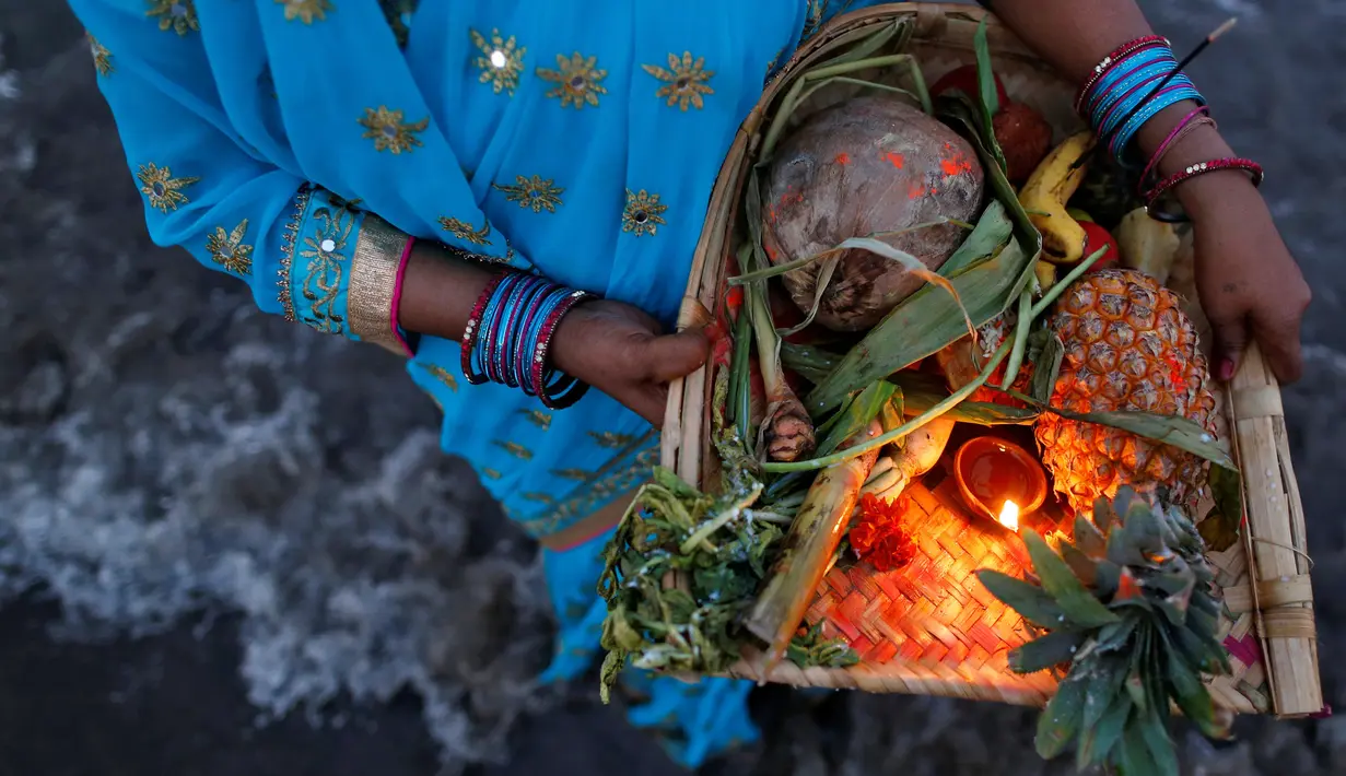 Seorang wanita membawa sesaji saat ritual Chhat Puja di Mumbai, India (7/11). Dalam ritual menyembah Dewa Matahari ini mereka meminta kesejahteraan, dan kemakmuran. (Reuters/Danish Siddiqui)