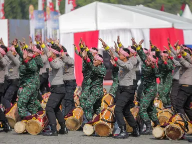 Prajurit TNI dan Polri berkolaborasi memainkan rampak gendang dalam HUT ke-73 Bhayangkara di Monas, Jakarta, Rabu (10/7/2019). HUT Bhayangkara ke-73 ini bertemakan ‘Dengan semangat Promoter, pengabdian Polri, untuk masyarakat, bangsa, dan negara. (Liputan6.com/Faizal Fanani)
