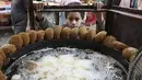 Seorang anak laki-laki Palestina menunggu sejumlah falafel di sebuah penjual di kota Hebron di Tepi Barat yang diduduki, selama bulan suci Ramadhan, Minggu (18/4/2021). Falafel adalah sebuah makanan Timur Tengah yang pada bulan Ramadhan, sering dimakan sebagai hidangan buka puasa. (HAZEM BADER/AFP)