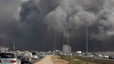 Mobil-mobil melaju saat asap hitam  membumbung menyelimuti gedung Stasiun Kereta Api Cepat Haramain di kota Jeddah, Arab Saudi, Minggu (29/9/2019). Akibat kebakaran tersebut, setidaknya sepuluh orang terluka. (Photo by - / AFP)