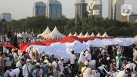 Massa membentangkan bendera Merah Putih saat mengikuti acara Munajat dan Maulid Akbar 2019 #ReuniMujahid212 di kawasan Monas, Jakarta, Senin (2/12/2019). Aksi dimulai dengan salat tahajud bersama pada pukul 03.00 WIB dan ditutup dengan doa yang berakhir pada 08.00 WIB. (Liputan6.com/Herman Zakharia)