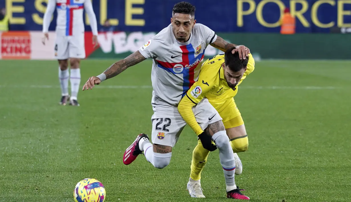 <p>Penyerang Barcelona, Raphinha berduel memperebutkan bola dengan pemain Villarreal, Alex Baena selama pertandingan lanjutan La Liga Spanyol di stadion Ceramica di Villarreal, Spanyol, Senin (13/2/2023). Barcelona menang tipis atas Villarreal dengan skor 1-0. (AP Photo/Alberto Saiz)</p>