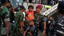 Seorang anggota TNI AD menggendong bocah dari keluarga eks Gafatar saat tiba di Tanjung Priok, Jakarta, Kamis (28/1/2016). Sebanyak 824 warga eks Gafatar dipulangkan dari Kalimantan untuk dikembalikan ke daerah asal. (Liputan6.com/Gempur M Surya)