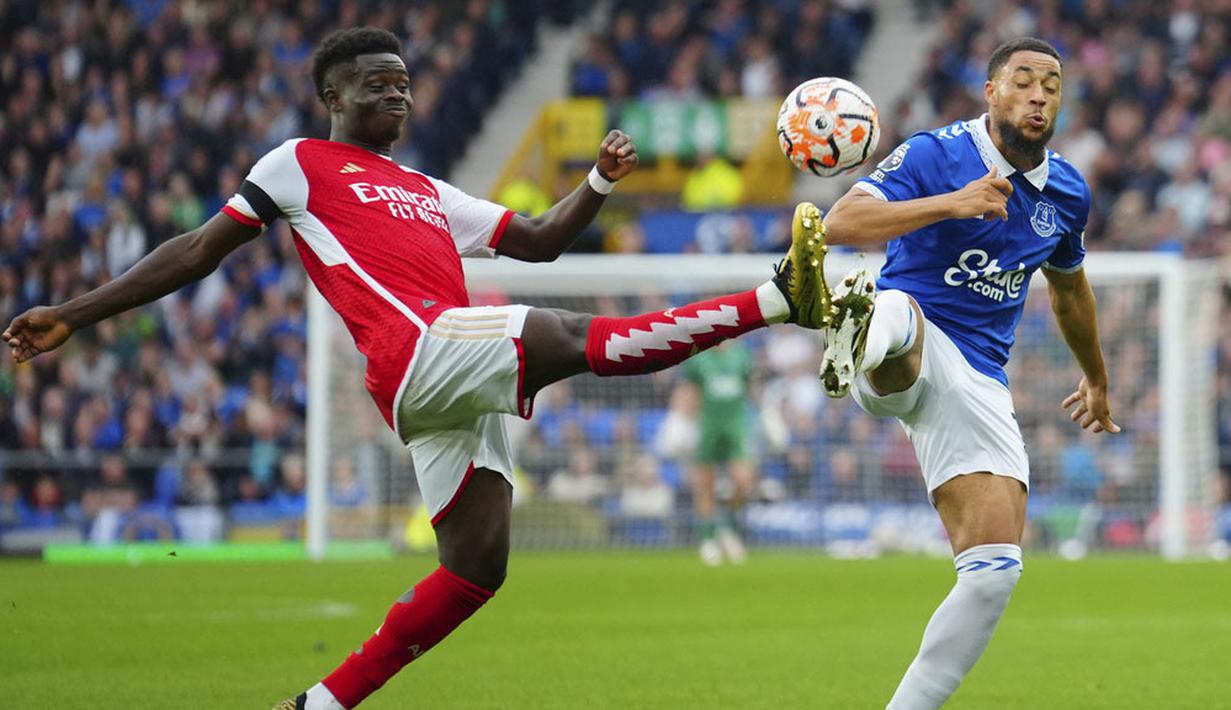 Pemain Arsenal, Bukayo Saka, berebut bola dengan pemain Everton, Arnaut Danjuma, pada laga Liga Inggris di Stadion Goodison Park, Minggu (17/09/2023). (AP Photo/Jon Super)
