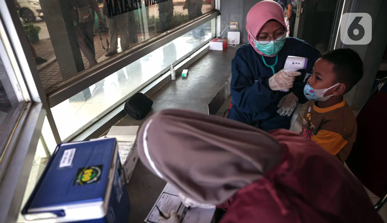 Petugas kesehatan mengecek suhu tubuh seorang anak saat vaksinasi COVID-19 Sinovac di Pospol Polsek Pamulang, Tangerang Selatan, Banten, Kamis (6/1/2022). Vaksinasi dilakukan guna mendukung tercapainya target nasional vaksinasi anak sebanyak 26 juta di seluruh Indonesia. (Liputan6.com/Faizal Fanani)