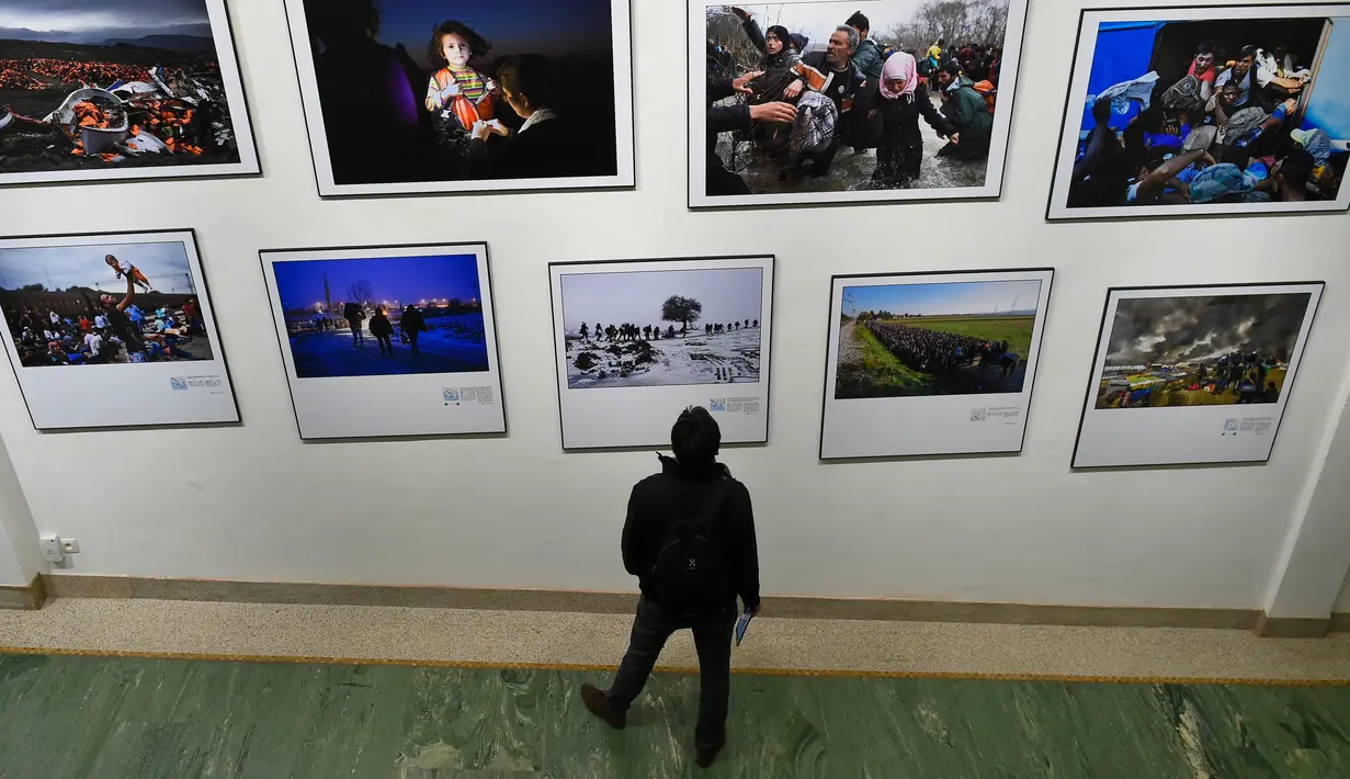 Pengunjung melihat foto karya fotografer Agence France-Presse (AFP) mengenai krisis migrasi di Eropa di pusat seni Bozar di Brussels (3/5). Pameran ini menampilkan foto-foto imigran dari Suriah, Irak sampai Turki dan Laut Tengah. (AFP Photo/John Thys)
