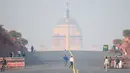 Orang-orang berjalan di dekat istana kepresidenan di tengah kondisi kabut asap tebal di New Delhi (15/11/2021). Otoritas kota New Delhi tengah mempertimbangkan penguncian wilayah akibat kian memburuknya polusi udara. (AFP/Money Sharma)