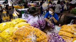 Seorang wanita mengemas anggrek menjelang Loy Krathong di pasar bunga Pak Khlong Talat, Bangkok, Kamis (18/11/2021). Bulan November ini Thailand akan mengadakan festival Loy Krathong di mana warga akan menghanyutkan keranjang berisi bunga dan lilin di sungai, kolam atau danau. (Jack TAYLOR/AFP)