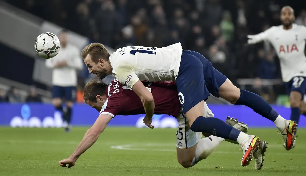 Penyerang Tottenham, Harry Kane berduel memperebutkan bola dengan pemain West Ham, Craig Dawson pada pertandingan perempat final Piala Liga Inggris di Stadion Tottenham Hotspur di London, Kamis (23/12/2021). Kemenangan mengantar Chelsea ke semifinal Piala Liga Inggris. (AP Photo/Rui Vieira)