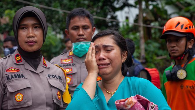 Seorang wanita menangis dekat Tim SAR saat menemukan keluarganya yang meninggal dalam bencara tanah longsor di Gowa, Sulawesi Selatan, Jumat (25/1). Hingga 25 Januari 2018, tercatat 33 orang meninggal dunia. (YUSUF WAHIL/AFP)