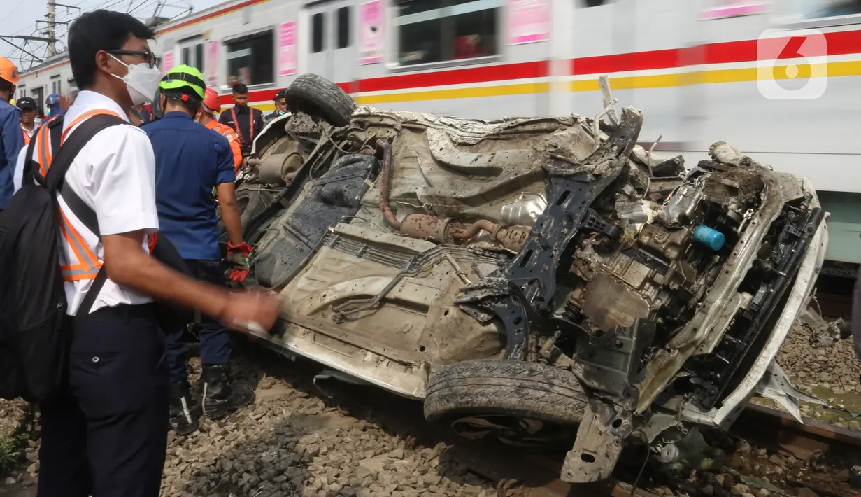 Kereta melintas di samping mobil Honda Mobilio yang tertabrak KRL Commuterline KA 1077 (Bogor-Jakarta Kota) di kawasan Rawageni, Ratu Jaya, Cipayung, Depok, Jawa Barat, Rabu (20/4/2022). Kecelakaan di perlintasan sebidang itu menyebabkan terganggunya perjalanan KRL. (merdeka.com/Arie Basuki)